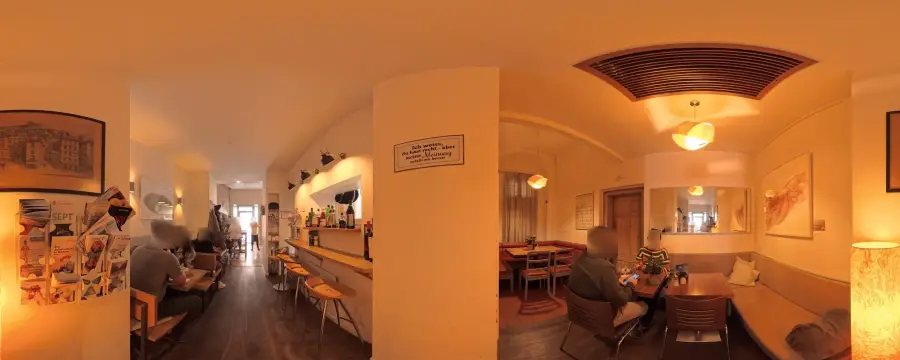 Der Gastraum: warmes Licht, Holzboden, Bar mit Hockern und gemütliche Sitzecke